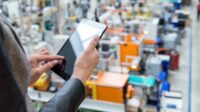 Businesswoman holding touchpad in manufacturing company