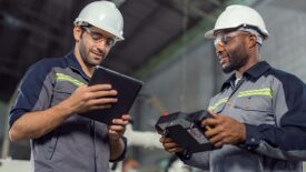 Two Industry engineers stand and discuss work in the factory workshop.