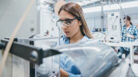 Female industrial worker working with manufacturing equipment in a factory.
