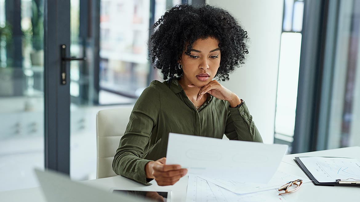 Shot of a young businesswoman going over paperwork in a modern office.