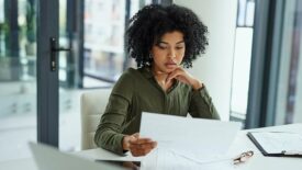 Shot of a young businesswoman going over paperwork in a modern office.