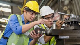 Two professional technicians working in an industrial plant, one holding a tablet.