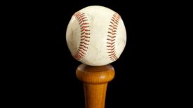 Baseball sitting on top of a bat handle with a black background.