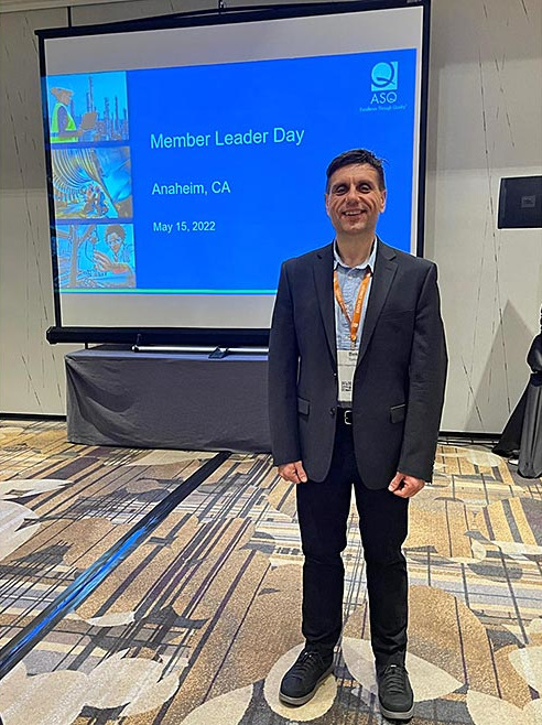 Dr. Tomic posing in front of a slide screen at the ASQ Member Leader Day in Anaheim, CA.