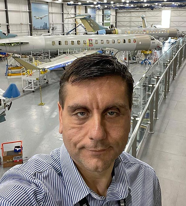 Selfie of Ben Tomic inside an airplane hangar.