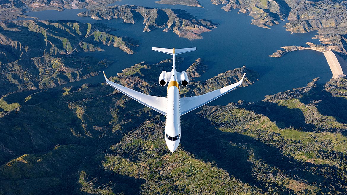 Overhead aerial shot of Bombardier flying over mountainous terrain.