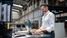 Mature businessman using laptop in a factory Mature businessman using laptop in a factory.