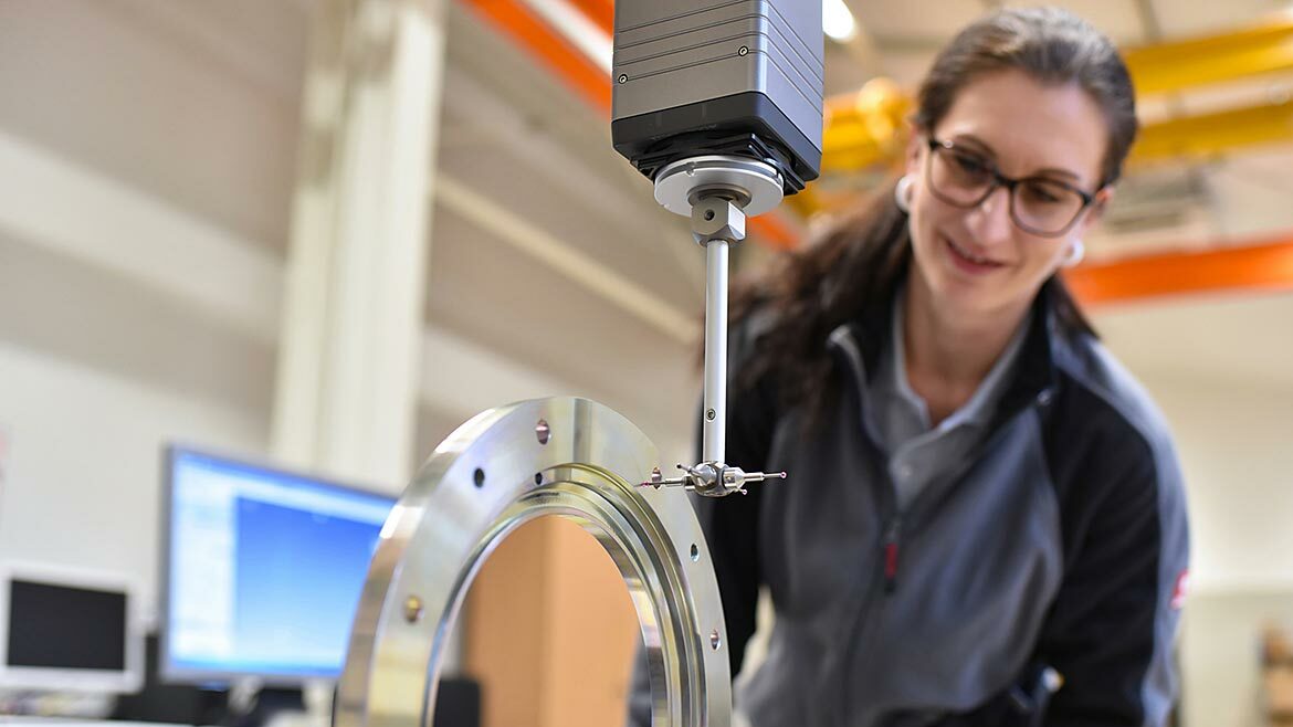 Woman working in quality control, measuring a workpiece.