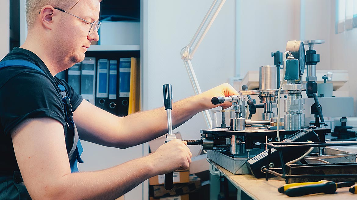 Professional calibration of pressure gauges and sensors. Working person sits at desk and is engaged in verification of instrumentation.