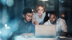 Cropped shot of three young businesspeople working together on a laptop in their office late at night.